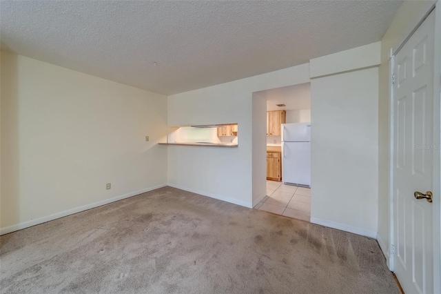 spare room featuring a textured ceiling and light colored carpet