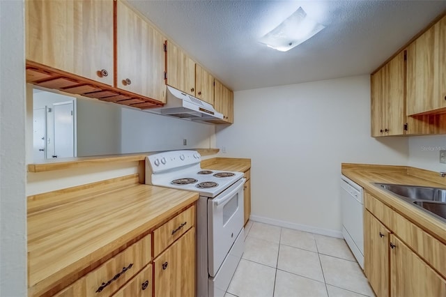 kitchen with white appliances, a textured ceiling, light brown cabinets, and light tile patterned flooring