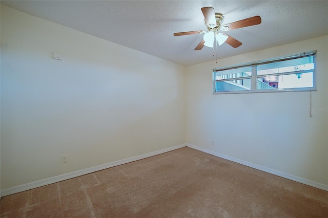 spare room featuring ceiling fan, light colored carpet, and a textured ceiling