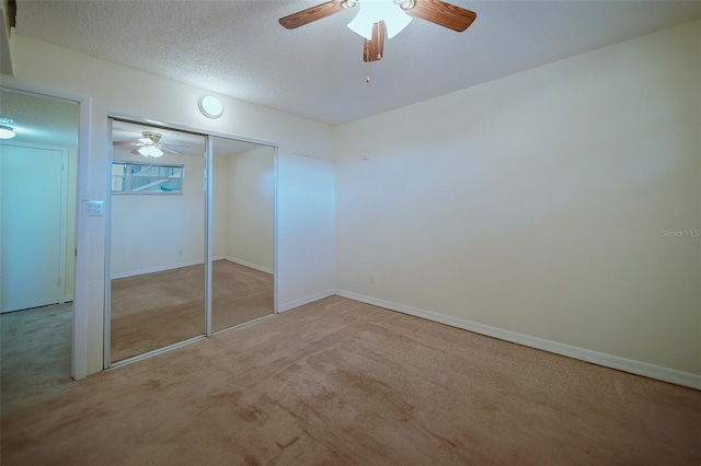 unfurnished bedroom featuring light carpet, a closet, ceiling fan, and a textured ceiling