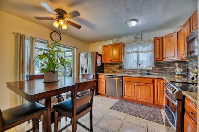 kitchen with ceiling fan, sink, stainless steel appliances, backsplash, and light tile patterned flooring