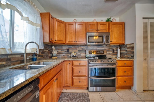 2011 Green Juniper Ln, Brandon, FL 33511 - kitchen with appliances with stainless steel finishes, a sink, brown cabinetry, light stone countertops, and tasteful backsplash