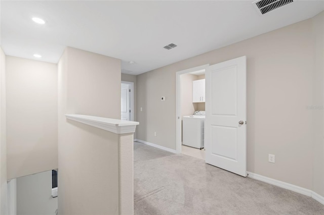 corridor with washer / clothes dryer and light carpet