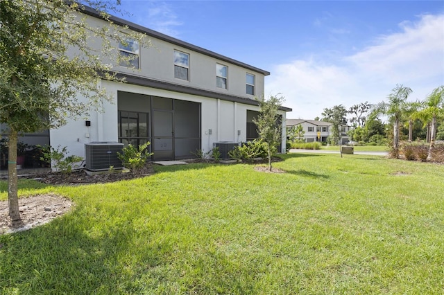 rear view of property with central air condition unit and a yard