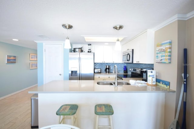 kitchen featuring pendant lighting, white cabinets, stainless steel appliances, and sink