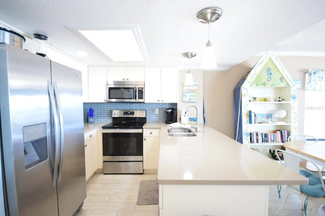 kitchen featuring sink, stainless steel appliances, backsplash, pendant lighting, and white cabinets