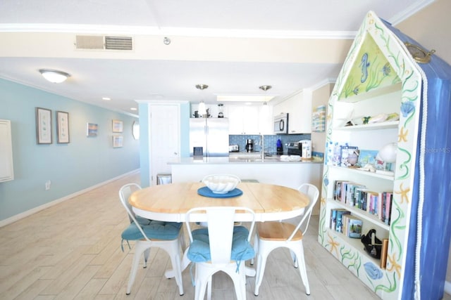 dining area featuring light hardwood / wood-style floors and ornamental molding