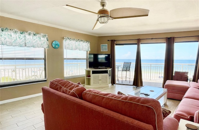 living room featuring light hardwood / wood-style floors, crown molding, ceiling fan, and a healthy amount of sunlight