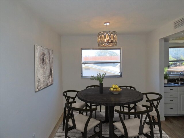 dining space with hardwood / wood-style flooring, plenty of natural light, a notable chandelier, and sink