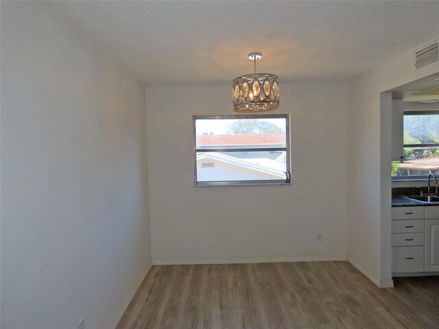 unfurnished room with a chandelier, sink, and wood-type flooring