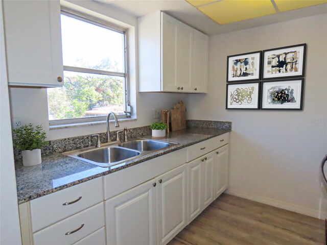 kitchen with white cabinets, sink, and light hardwood / wood-style flooring