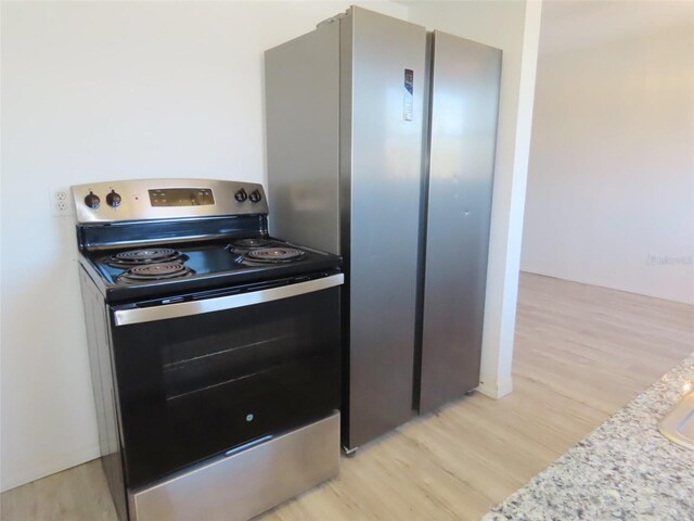 kitchen with light stone counters, light hardwood / wood-style flooring, and stainless steel electric range