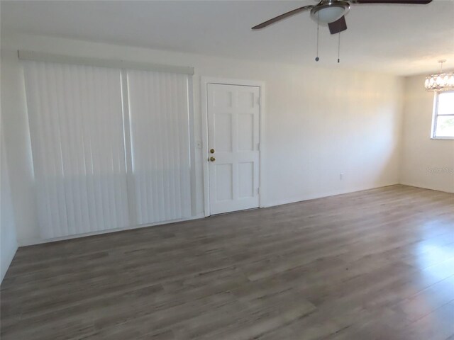 spare room featuring ceiling fan with notable chandelier and dark hardwood / wood-style floors