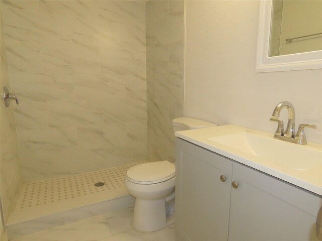 bathroom featuring a tile shower, vanity, and toilet