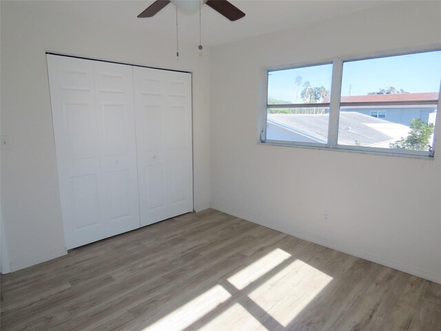 unfurnished bedroom with light wood-type flooring, a closet, and ceiling fan