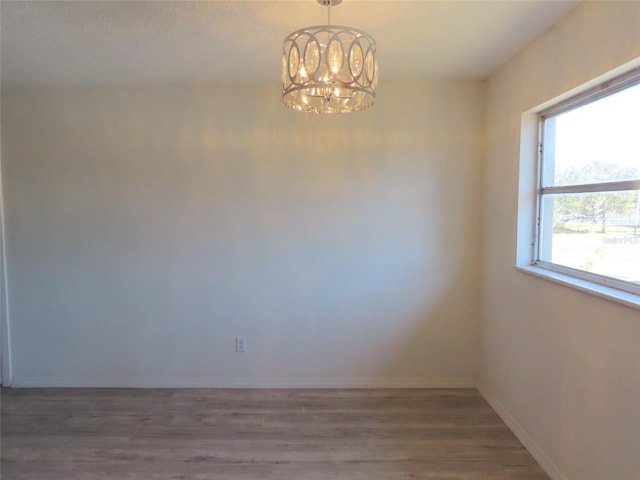 spare room featuring dark wood-type flooring and a notable chandelier