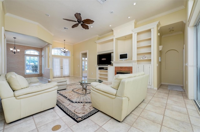 living room with french doors, ceiling fan with notable chandelier, crown molding, built in features, and light tile patterned flooring