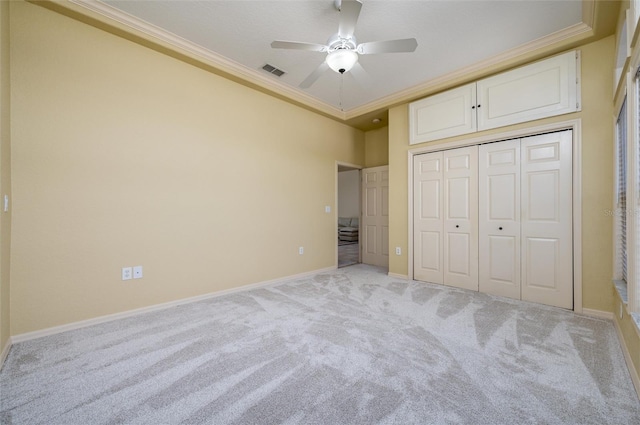 unfurnished bedroom with a closet, ceiling fan, crown molding, and light colored carpet