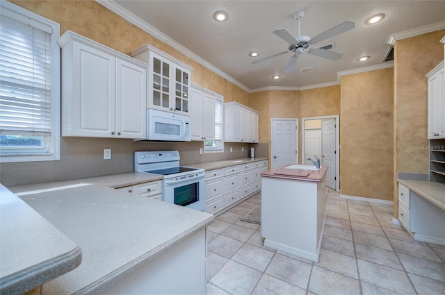 kitchen with white appliances, white cabinetry, a healthy amount of sunlight, and crown molding