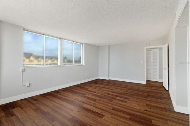 spare room featuring a textured ceiling and dark hardwood / wood-style floors