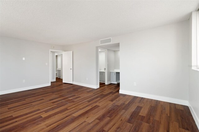 empty room featuring a textured ceiling and dark hardwood / wood-style floors