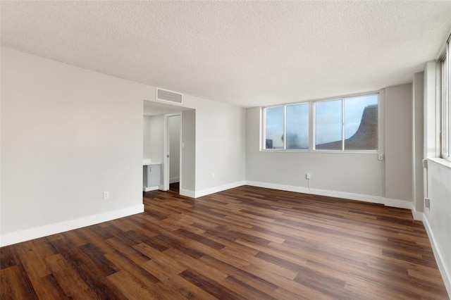 empty room featuring a textured ceiling and dark hardwood / wood-style floors