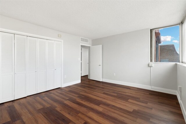 unfurnished bedroom with a closet, a textured ceiling, and dark hardwood / wood-style floors