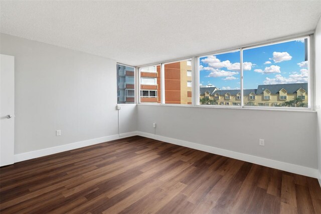 empty room with a textured ceiling, floor to ceiling windows, and dark wood-type flooring