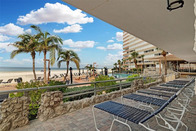 view of patio with a beach view, a balcony, and a water view