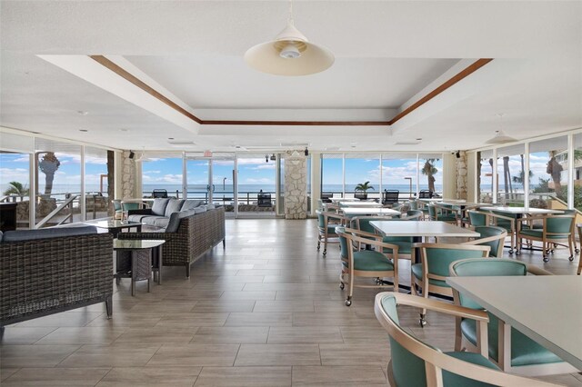 dining space with a raised ceiling, a healthy amount of sunlight, and a wall of windows