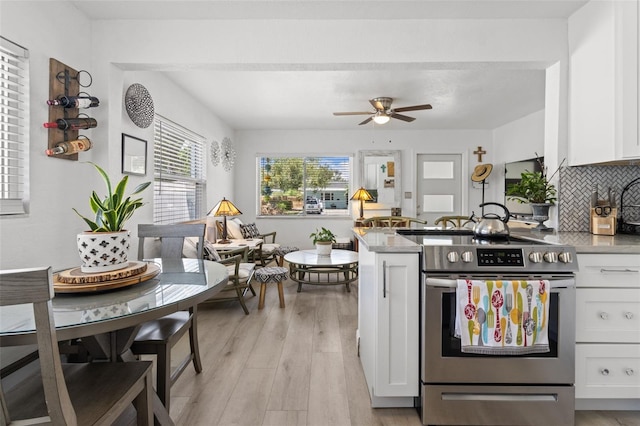 kitchen with stainless steel electric stove, tasteful backsplash, white cabinets, ceiling fan, and light hardwood / wood-style flooring