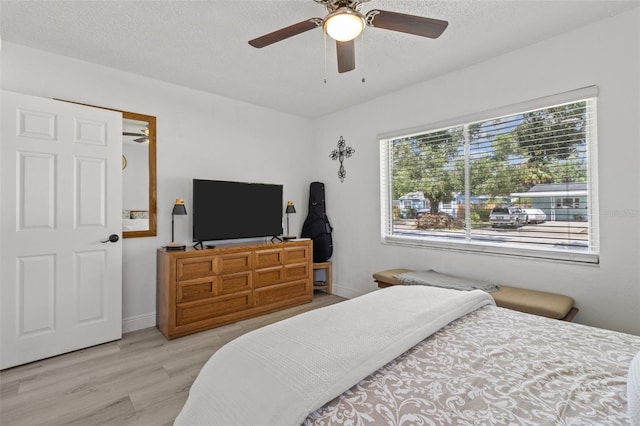 bedroom with a textured ceiling, ceiling fan, and light hardwood / wood-style flooring