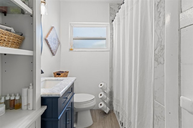 bathroom with walk in shower, vanity, and toilet