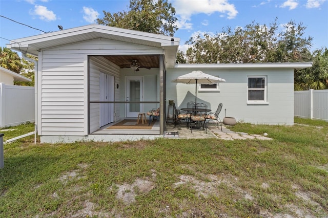 back of property with ceiling fan, a yard, and a patio area