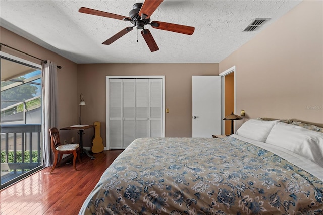 bedroom with access to outside, ceiling fan, dark wood-type flooring, a textured ceiling, and a closet