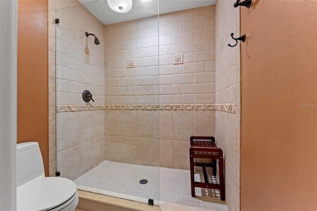 bathroom with a tile shower and toilet