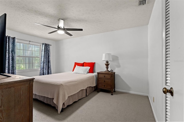 carpeted bedroom featuring ceiling fan and a textured ceiling