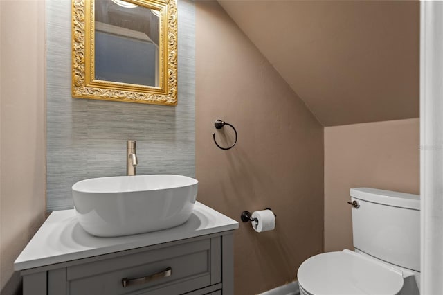 bathroom with vanity, toilet, and vaulted ceiling