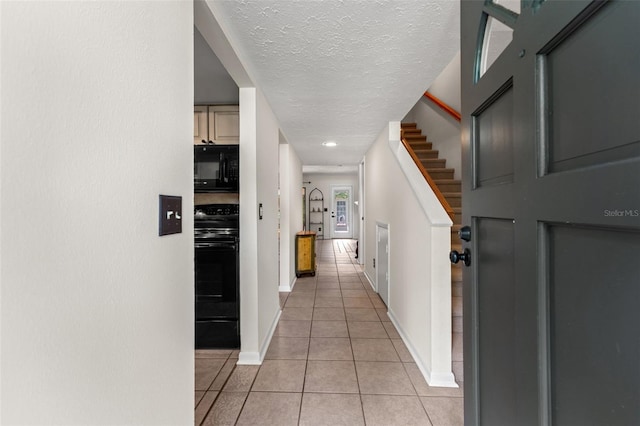 hallway featuring light tile patterned floors and a textured ceiling