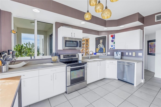 kitchen with pendant lighting, light tile patterned floors, white cabinets, appliances with stainless steel finishes, and sink