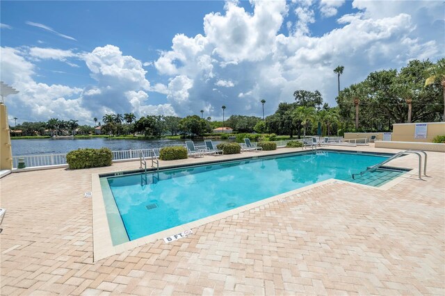 view of swimming pool with a patio area and a water view