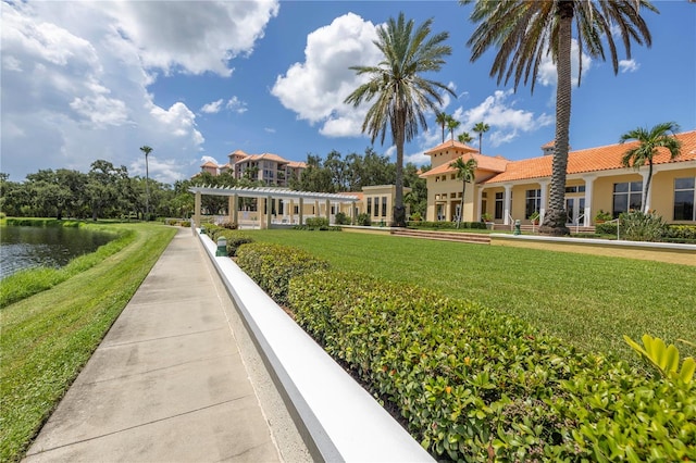 exterior space with a pergola, a water view, and a lawn