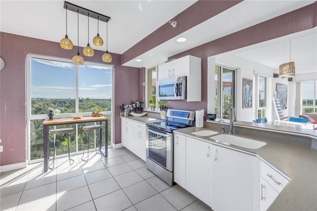 kitchen with appliances with stainless steel finishes, hanging light fixtures, white cabinetry, and sink