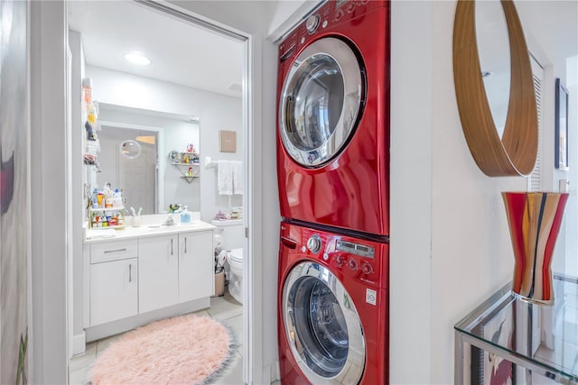 laundry room featuring stacked washer and clothes dryer and light tile patterned floors