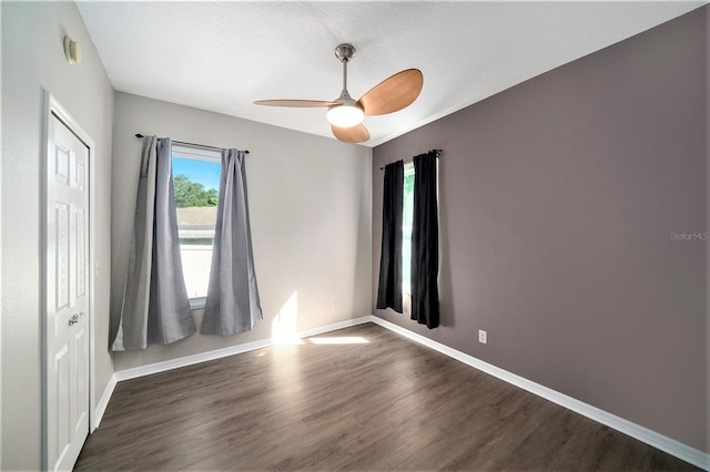 unfurnished room featuring dark wood-type flooring and ceiling fan