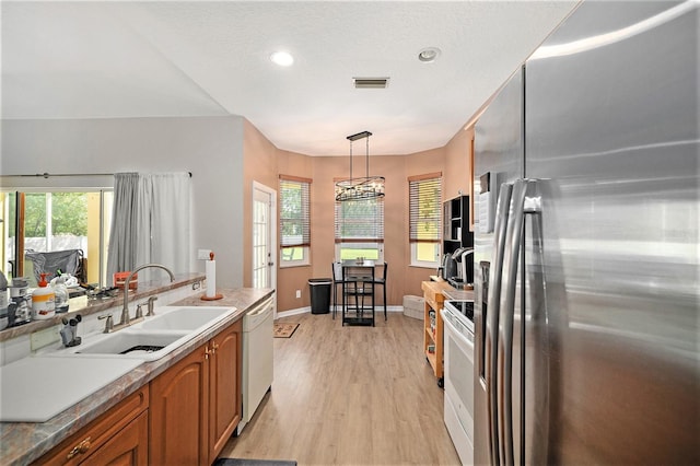 kitchen with a chandelier, white appliances, light hardwood / wood-style flooring, sink, and hanging light fixtures