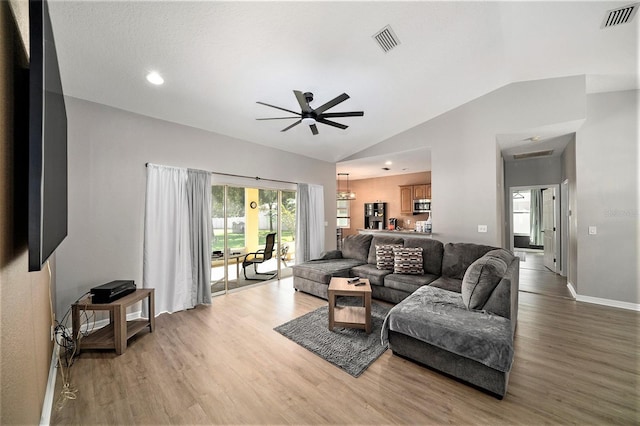 living room with ceiling fan, light hardwood / wood-style flooring, and vaulted ceiling