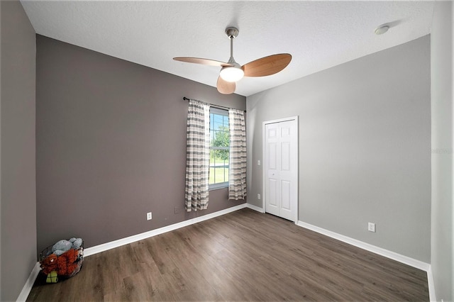 empty room featuring dark hardwood / wood-style flooring, a textured ceiling, and ceiling fan