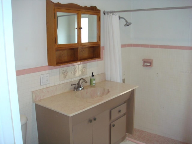 bathroom with tile walls, toilet, vanity, and walk in shower