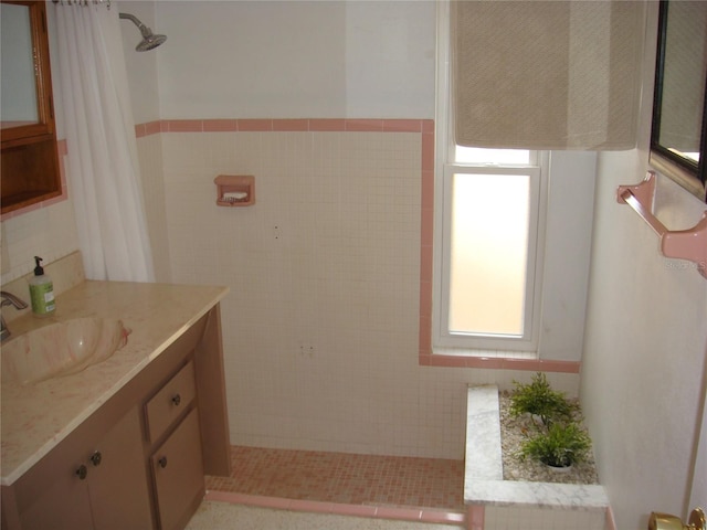 bathroom with walk in shower, vanity, and tile walls